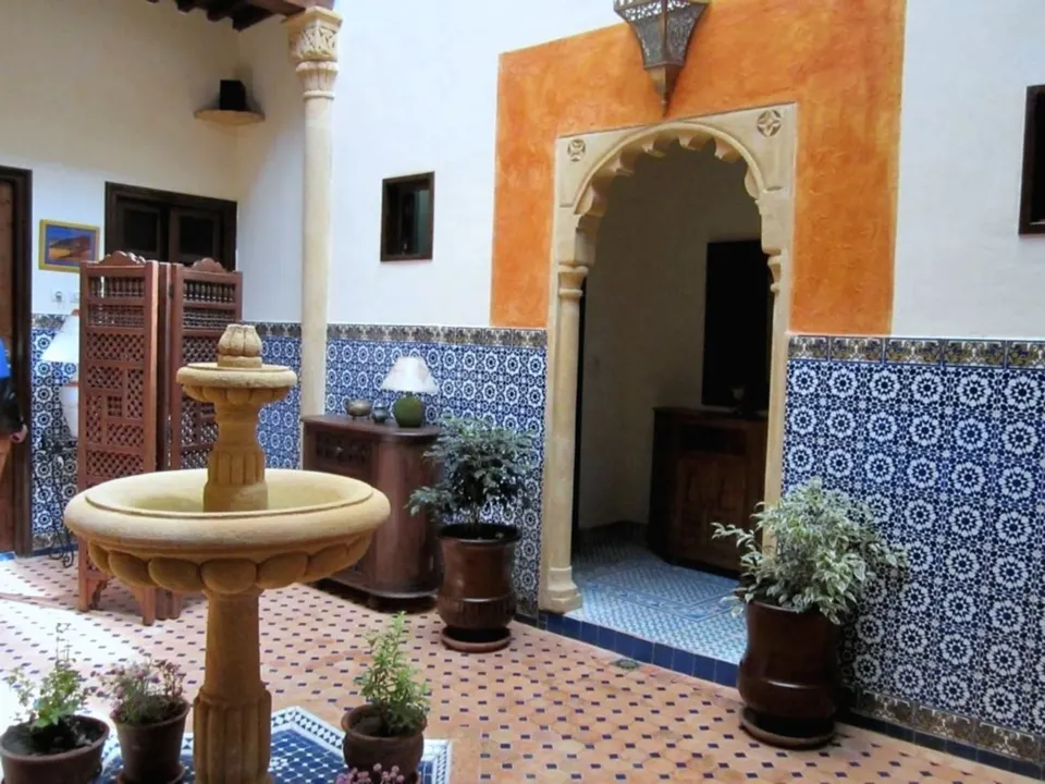 The patio: stone fountain, an orange arch and potted plants