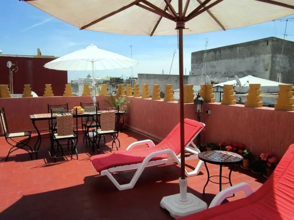 The roof terrace: red walls, mustard crenellations, parasols and loungers over the medina roofs